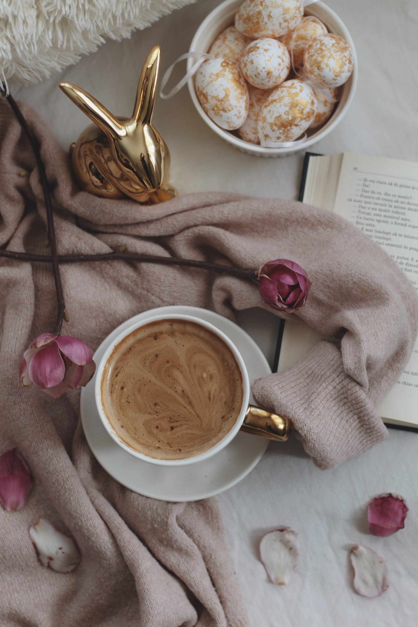 Flatlay of coffee, an Easter-egg bowl, and an open book